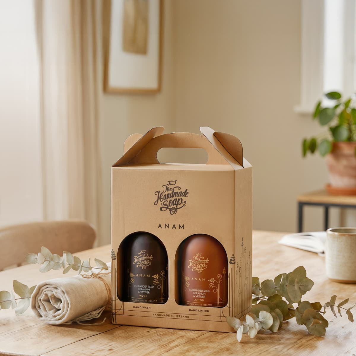 Two bottles in a cardboard gift box on a table with a neutral background